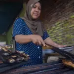 Pedagang menyiapkan ikan "tuing-tuing tapa" atau ikan terbang bakar khas Kabupaten Majene pesanan pembeli di salah satu ruas jalan di Desa Labuan Somba, Kecamtan Cendana, Kabupaten Majene, Sulawesi Barat, Minggu (30/4/2023). bmzIMAGES/Basri Marzuki