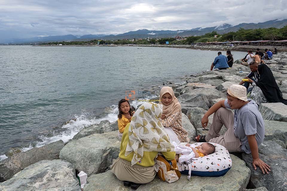 Pengunjung membawa bayinya saat berlibur di Pantai Kampung Nelayan di Palu, Sulawesi Tengah, Kamis (11/4/2024). Sejumlah tempat wisata pantai di wilayah itu ramai dikunjungi warga setempat untuk mengisi waktu liburan lebaran Idul Fitri. (bmzIMAGES/Basri Marzuki)