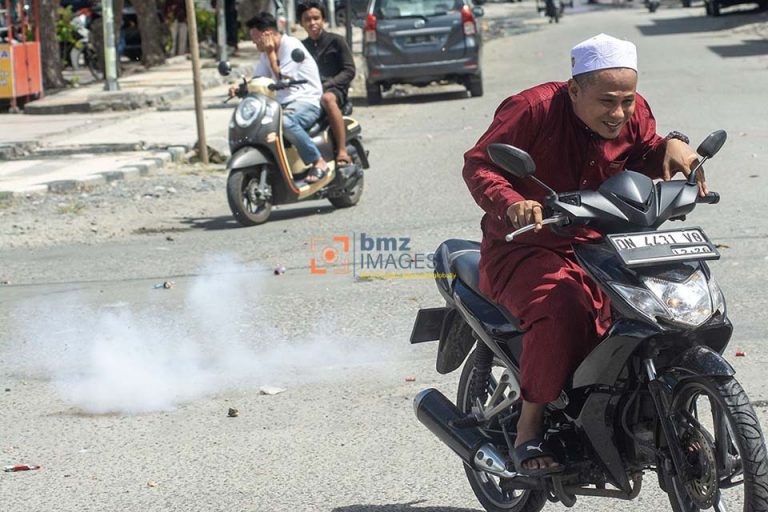 Pengendara sepeda motor mencoba menghindari ledakan petasan saat digelar Lebaran Iwwad atau Lebaran Arab di Palu, Sulawesi Tengah, Kamis (11/4/2024).
