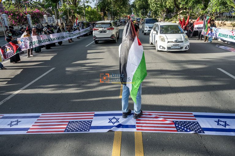 Sejumlah warga yang menamakan diri dari Barisan Aliansi Resistensi Al-Aqsha (Baraq) menggunakan simbol bendera Israel dan Amerika Serikat sebagai alas saat berunjukrasa di Palu, Sulawesi Tengah, Jumat (5/4/2021).