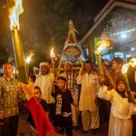 Warga berkeliling kampung sambil mengusung untaian makanan yang diikat di atas wadah diiringi pawai obor pada tradisi Lebaran Mandura di Kampung Baru, Palu, Sulawesi Tengah, Selasa (16/4/2024). Lebaran Mandura adalah tradisi tahunan yang digelar warga setempat setelah hari ketujuh lebaran Idul Fitri dengan mengarak Mandura atau makanan khas lebaran yang terbuat dari tiga jenis beras ketan yang dibungkus dengan daun pisang untuk disantap bersama. bmzIMAGES/Basri Marzuki