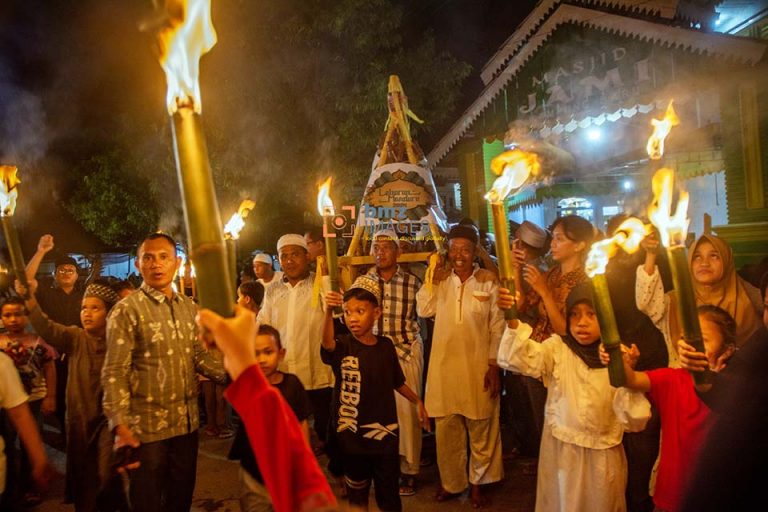 Warga berkeliling kampung sambil mengusung untaian makanan yang diikat di atas wadah diiringi pawai obor pada tradisi Lebaran Mandura di Kampung Baru, Palu, Sulawesi Tengah, Selasa (16/4/2024). Lebaran Mandura adalah tradisi tahunan yang digelar warga setempat setelah hari ketujuh lebaran Idul Fitri dengan mengarak Mandura atau makanan khas lebaran yang terbuat dari tiga jenis beras ketan yang dibungkus dengan daun pisang untuk disantap bersama. bmzIMAGES/Basri Marzuki