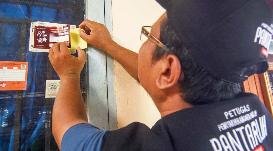 Panitia Pemutakhiran Data Pemilih menempelkan stiker tanda sudah dilakukan pencocokan dan penelitian (Coklit) pemilih di rumah warga di Kelurahan Palupi, Palu, Sulawesi Tengah, Selasa (28/2/2023). (Foto: bmzIMAGES/Basri Marzuki)