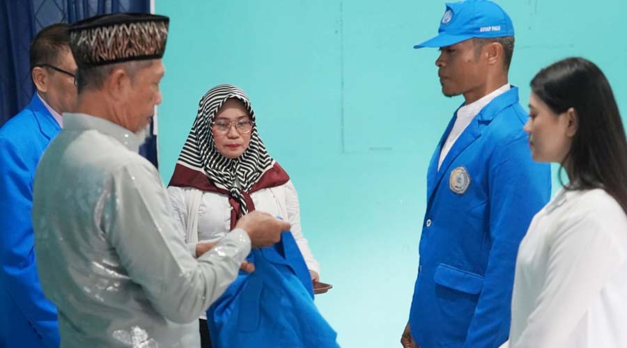 Wali Kota Palu diwakili Asisten Bidang Pemerintahan dan Kesra Setda Kota Palu, Usman (kiri) bersiap mengenakan jaket ke mahasiswa peserta KKN Angkatan XXIV STIAP Pembangunan Palu, Sabtu (6/7/2024). (Foto: Prokopim Sekkot Palu/Iwan)