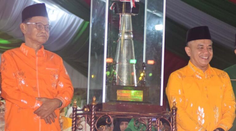 Gubernur Sulteng Rusdy Mastura (kiri) bersama Wali Kota Palu, Hadianto Rasyid berdiri mengapit piala setelah Kota Palu dinobatkan sebagai Juara Umum MTQ XXX TIngkat Provinsi Sulteng pada seremoni penutupan di Lapangan Untad, Palu, Jumat (26/7/2024) malam. (Foto: prokopim Setda Kota Palu/Imron)