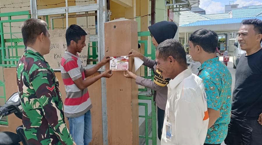 Bhabinkamtibmas bersama warga menempelka stiker berisi imbauan Pilkada damai di Palu, Rabu (17/7/2024). (Foto: HO-Humas Polresta Palu)