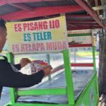 PS. Kasubsi PIDM Polresta Palu, Aiptu I Kadek Aruna (kiri) turun langsung menemplekan stiker pad asebuah gerobak dagangan di Palu, Rabu (17/7/2024). (Foto: HO-Humas Polresta Palu)