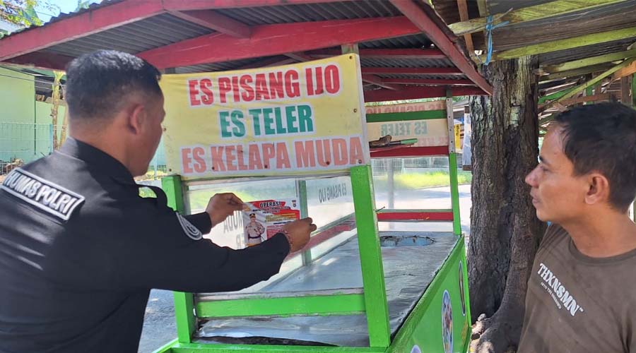 PS. Kasubsi PIDM Polresta Palu, Aiptu I Kadek Aruna (kiri) turun langsung menemplekan stiker pad asebuah gerobak dagangan di Palu, Rabu (17/7/2024). (Foto: HO-Humas Polresta Palu)