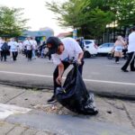 Seorang peserta jalan santai memungut sampah pada Sinergi Lestari PT Vale di Makassar, Minggu (28/7/2024). (Foto: PT Vale)
