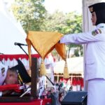 Wali Kota Palu, Hadianto Rasyid (kiri) mencium bendera Merah Putih sebelum memneyrahkan ke Paskibra untuk dikibarkan pdaa upacara peringatan HUT ke-79 Kemerdekaan RI di Lapangan Kantor Wali Kota Palu, Sabtu *17/8/2024). (Foto: Pemkot palu)