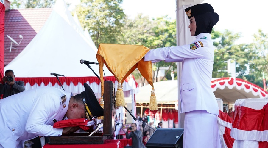 Wali Kota Palu, Hadianto Rasyid (kiri) mencium bendera Merah Putih sebelum memneyrahkan ke Paskibra untuk dikibarkan pdaa upacara peringatan HUT ke-79 Kemerdekaan RI di Lapangan Kantor Wali Kota Palu, Sabtu *17/8/2024). (Foto: Pemkot palu)