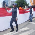 Bakal pasangan calon Wali Kota dan Wakil Wali Kota Palu, Hidayat dan Andi Nur B Lamakarate berjalan di antara bentangan bendera Merah Putih di tugu 0 kilometer, Minggu (18/8/2024). (Foto: Tim Handal)