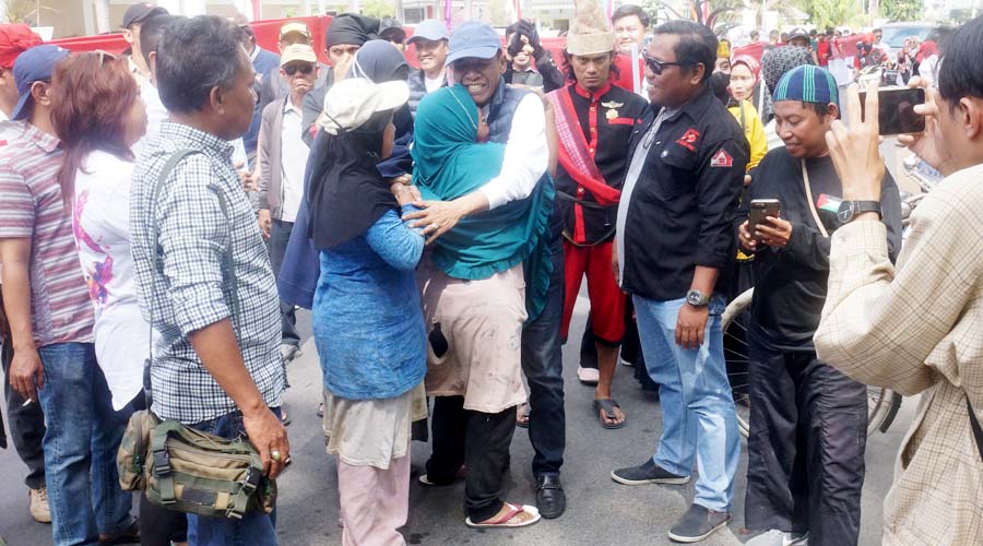 Seorang ibu memeluk bakal calon Wali Koat Palu, Hidayat dan mengadukan gerobaknya yang disita oleh pemerintah di Tmaan GOR Palu, Minggu (18/8/2024). (Foto: Tim Handal)