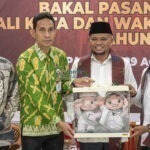 Ketua KPU Kota Palu, Idrus (kedua kiri) bersama Ketua Bawaslu Kota Palu, Agussalim Wahid (kiri) menyerahkan maskot pilkada kepada pasangan bakal calon Wali Kota Palu Muhammad J Wartaboe (kedua kanan) dan baal calon Wakil Walik Kota Palu, Rizal (kanan) usai pendaftaran di Kantor KPU Kota Palu, Kamis (29/8/2024). (Foto: bmzIMAGES/Basri Marzuki)