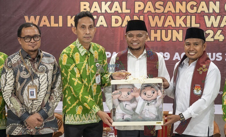 Ketua KPU Kota Palu, Idrus (kedua kiri) bersama Ketua Bawaslu Kota Palu, Agussalim Wahid (kiri) menyerahkan maskot pilkada kepada pasangan bakal calon Wali Kota Palu Muhammad J Wartaboe (kedua kanan) dan baal calon Wakil Walik Kota Palu, Rizal (kanan) usai pendaftaran di Kantor KPU Kota Palu, Kamis (29/8/2024). (Foto: bmzIMAGES/Basri Marzuki)