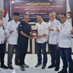 Ketua KPU Sigi, Soleman (keempat kiri) menyerahkan cinderamata kepada Moh Irwan Lapata selaku Ketua Tim Pemenangan pasangan Rizal Intjenae-Samuel Yansen Pongi usai mendaftar di KPU Sigi, Rabu (28/8/2024). (Foto: ist)