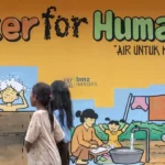 Sejumlah anak korban bencana melintas di depan mural yang dibuat untuk memperingati Hari Air Sedunia di kompleks Hunian Sementara (Huntara) Duyu, Palu, Sulawesi Tengah, Sabtu (23/3/2019). (bmzIMAGES/Basri Marzuki)