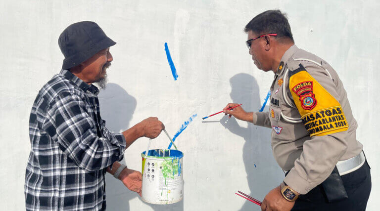 Kasubdit Kamseltibcar lantas Kompol Abu Bakar Djafar menorehkan kuasnya ke dindng menandai pembukaan lomba mural di Layana, Palu, Sabtu (14/9/2024). (Foto: Humas Polda Sulteng)