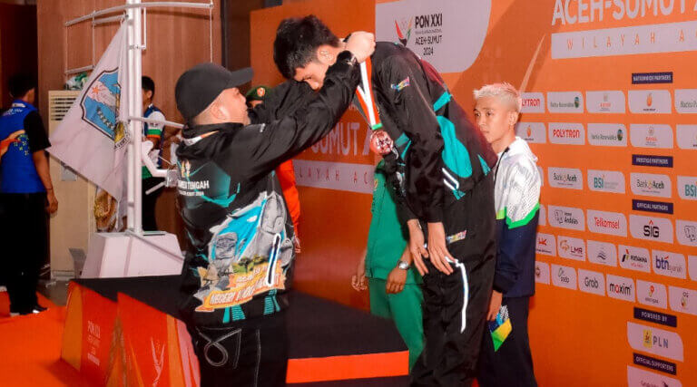 Atlet Muaythai Sulteng, Hikmal mendapat pengalungan medali perunggu pada PON XXI Aceh-Sumut, Selasa (19/2024). (Foto: Tima Media PON Sulteng)