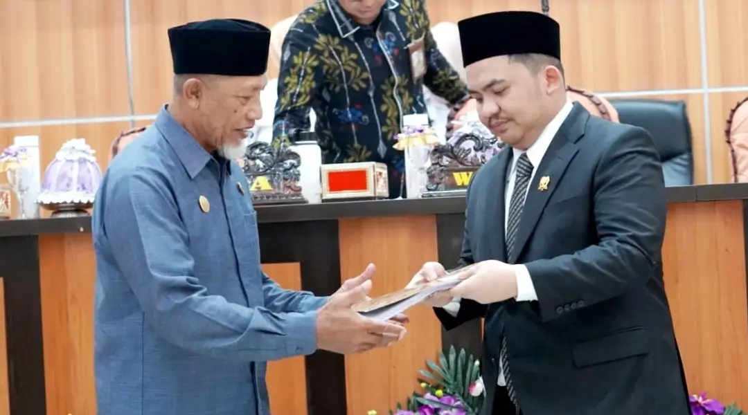 Wakil Ketua DPRD Kota Palu, Moh Anugrah Pratama (kanan) menyerahkan naskah kepada Asisten Bidang Pemerintah dan Kesra Setda Kota Palu pada rapat paripurna DPRD Kota Palu, Rabu (9/10/2024). (Foto: Prokopim Setda Kota Palu/Iwan)
