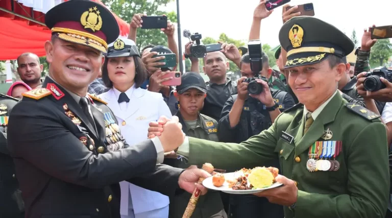 Kapolda Sulteng, Irjen Pol Agus Nugroho (kiri) menyerahkan tumpeng kepada seorang Pamen TNI pada perayaan HUT ke-t9 TNI di Mayonif 711 Raksatama, Palu, Sabtu (5/10/2024). (Foto: Humas Polda Sulteng)