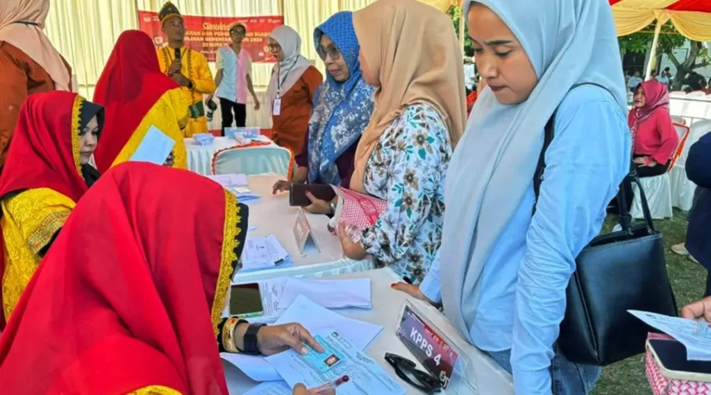 Petugas memverifikasi identitas warga sebelum mencoblos pada simulasi pemungutan suara yang digelar KPU Kota Palu di Lapangan Telkom Palu, Kamis (21/11/2024). (Foto: ist)
