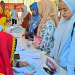 Petugas memverifikasi identitas warga sebelum mencoblos pada simulasi pemungutan suara yang digelar KPU Kota Palu di Lapangan Telkom Palu, Kamis (21/11/2024). (Foto: ist)
