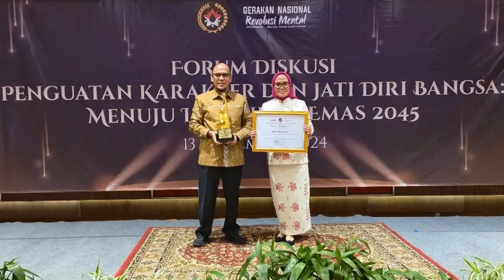 Sekkot Palu, Irmayanti )kanan) bersama Kepala Kesbangpol Kota Palu, Ansyar Sutiadi menunjukkan piagam dan tropi Anugerah Revolusi Mental di Jakarta, Rabu (13/11/2024). (Foto: Prokopim Setda Kota Palu)