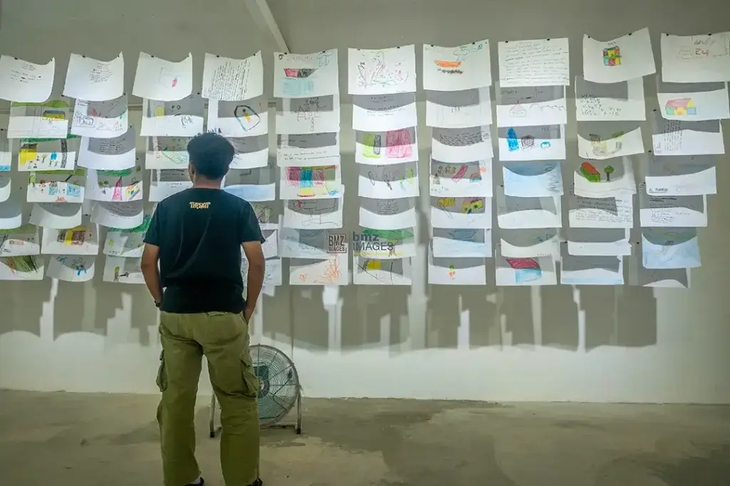 Pengunjung mengamati berbagai tulisan cerita dan gambar dari anak-anak pada pameran bertajuk Yang Kitorang Rasa Waktu Gempa di Palu, Sulawesi Tengah, Senin (4/11/2024). (bmzIMAGES/Basri Marzuki)
