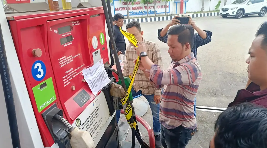 Petugas memasang Police Line saat menyegel dispenser BBM di SPBU di Jalan SIs Lajufri Palu, Selasa (10/12/2024). (Foto: Humas Polresta Palu)