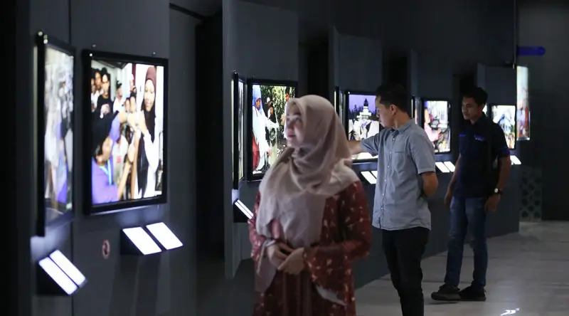 Pengunjung mengamati foto-foto bertajuk "Setelah Gelombang Reda" yang dipamerkan di Museum Tsunami Aceh, Kamis (6/2/2025). (Foto: UNIC Indonesia)