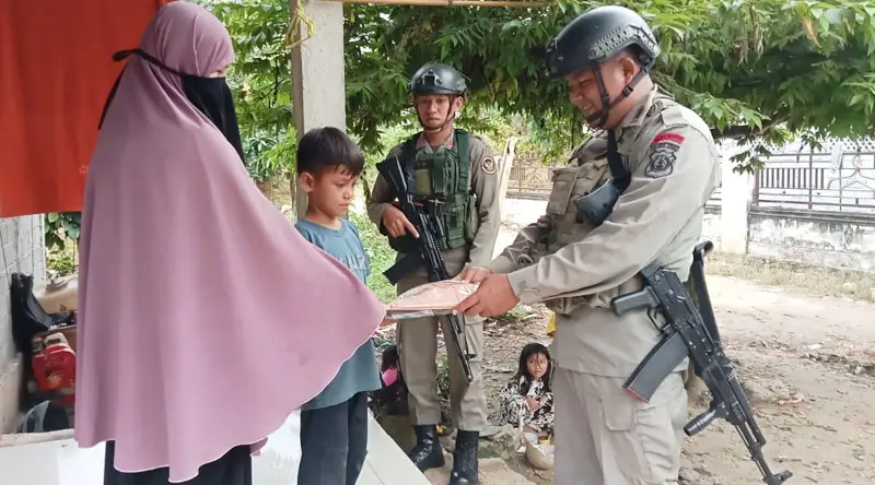 Personel Satagas Madago Raya menyerahkan seragam Merah Putih kepada seorag anak di wilayah Operasi, Poso, Minggu (9/2/2025). (Foto: HUmas Ops Madago Raya)