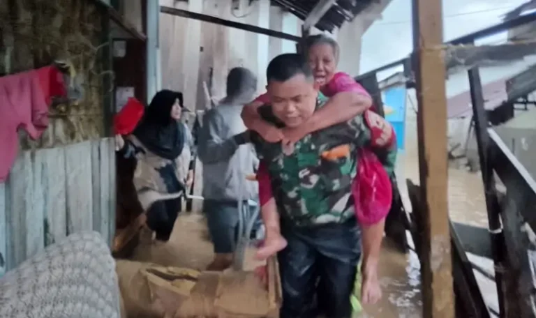 Kopda Yance menggendong Indo Asse yang terperangkap banjir di Duyu, Plau, Jumat (25/4/2025). (Foto: Penrem 132/Tdl)