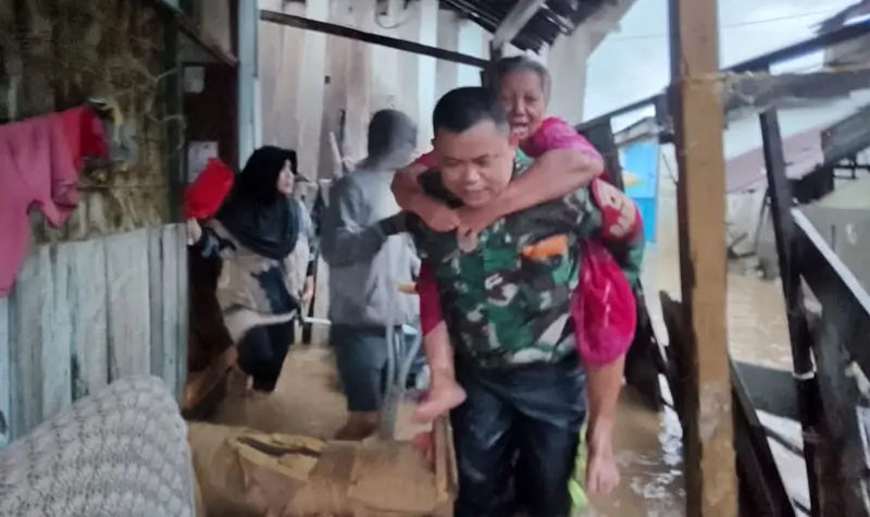Kopda Yance menggendong Indo Asse yang terperangkap banjir di Duyu, Plau, Jumat (25/4/2025). (Foto: Penrem 132/Tdl)