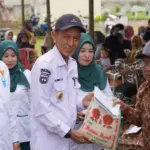 Kadis Kesehatan Kota Palu, dr. Rochmat Jasin (tengah) menyerahkan bantuan beras dari bazans Kota Palu ke warga di Tawaili, Rabu (4/6/2025). (Foto: Prokopim Stda Kota Palu/Jufri)