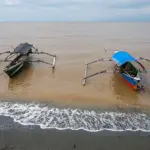 Perahu nelayan tertambat di bibir pantai Tambarana yang berwarno coklat terpapar limbah tambang emas, Rabu (18/6/2025). (bmzIMAGES)