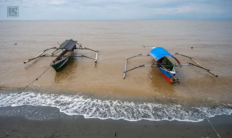 Perahu nelayan tertambat di bibir pantai Tambarana yang berwarno coklat terpapar limbah tambang emas, Rabu (18/6/2025). (bmzIMAGES)