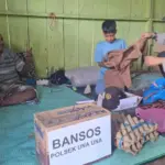 Kapolsek Unauna, AKP Mustarim Abbas memakaikan pakain sekolah kepada bocah Galang yang viral karena putus sekolah setelah ayahnya lumpuh di Wakai, Tojo Unauna, Jumat (13/5/2025). (Foto: Humas Polrs Tojo Unauna)