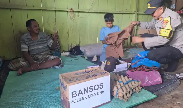 Kapolsek Unauna, AKP Mustarim Abbas memakaikan pakain sekolah kepada bocah Galang yang viral karena putus sekolah setelah ayahnya lumpuh di Wakai, Tojo Unauna, Jumat (13/5/2025). (Foto: Humas Polrs Tojo Unauna)