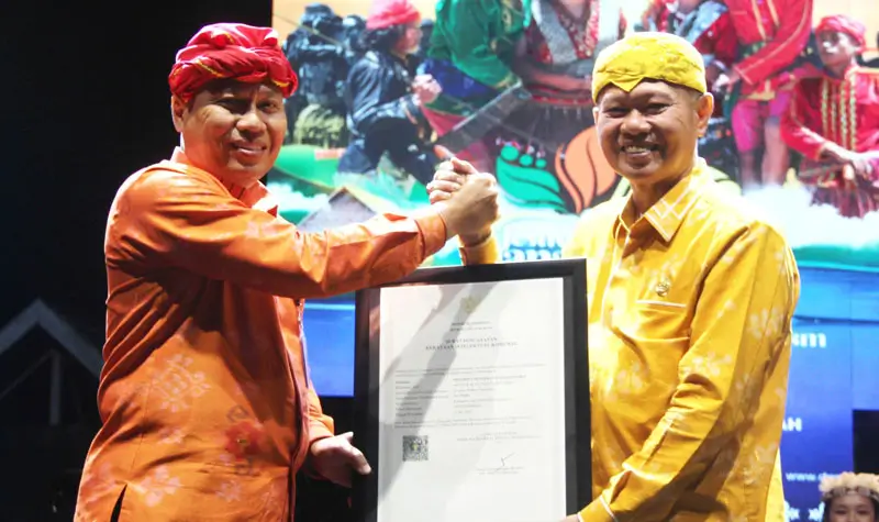 Kakanwil Kemenkum Sulteng Rakhmat Renaldy (kiri) menyerahkan sertifikat KIK ke Bupati Sigi Moh Rizal Intjenae pada pembukaan Festival; Danau Lindu 2025 di Lindu, Sigi, Jumat (18/7/2025). (@Kanwi Kemenkum Sulteng)