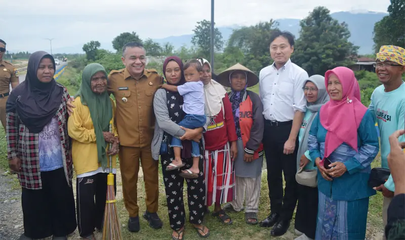 Wali Kota Iwanuma, , Jepang, Jun'ichi Satō bersama Wali Kota Palu Hadianto Rasyid berfoto bersama warga di lekasi eks likuifaksi Petobo, Selasa (15/7/2025). (Foto: Prokopim Setda Kota Palu/Imron)