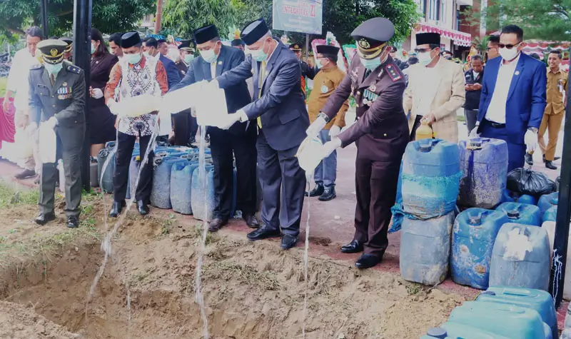 Kapolres Sigi bersama Bupati Sigi dan unsur Forkopimda menuangkan cap tikus ke dalam luabgn pada pemusnahan miras sebanyak 2 ton di Maplres Sigi, Selasa (1/7/2025). (Foto: Humas Polres Sigi)