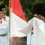 Salah seorang anggota Paskibraka mencium bendera merah putih pad apengukuhan di Taman nasional, Sab tu (16/8/2025). (©Prokopim Setda Kota Palu/Imron)