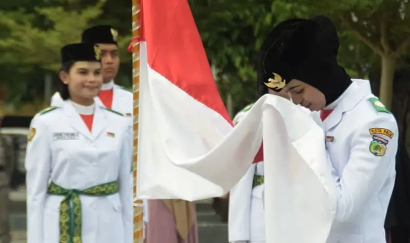 Salah seorang anggota Paskibraka mencium bendera merah putih pad apengukuhan di Taman nasional, Sab tu (16/8/2025). (©Prokopim Setda Kota Palu/Imron)