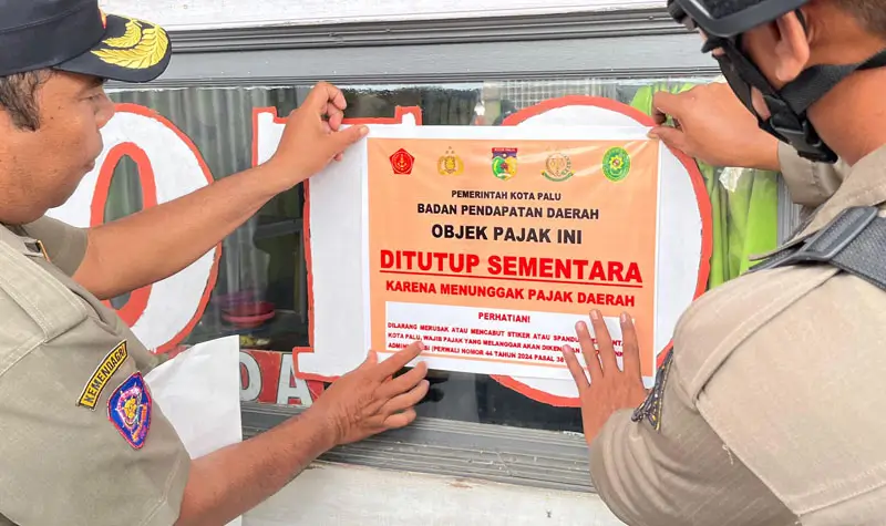 Petugas menempel stiker tanda penyegelan tempat usaha yang menunggak pajak di Kota Palu, Selasa (5/8/2025). (©Prokopim Setda Kota Palu/Jufri)