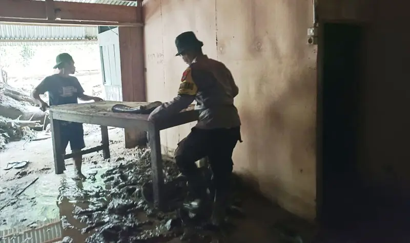 Anggota polis membantu warga memebrsihkan lumpur yang menggenangi rumah warga pasacabanjir bandang di Desa Namo, Sigi, Jumat (15/8/2025). (©Huams Polres Sigi)