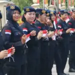 Sejumlah personel Brimob Polda Sulteng berdiri di pinggir jalan untuk membagikan bendera merah putih kepad apengendara, Minggu (3/8/2025). (©Humas Polda Sutleng)