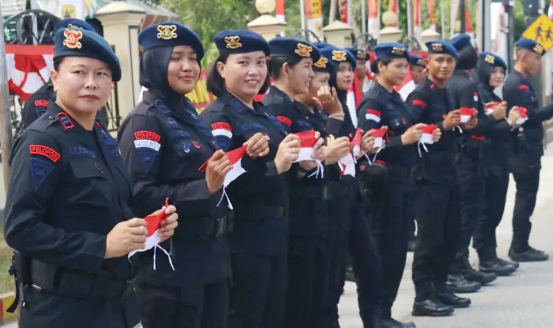 Sejumlah personel Brimob Polda Sulteng berdiri di pinggir jalan untuk membagikan bendera merah putih kepad apengendara, Minggu (3/8/2025). (©Humas Polda Sutleng)