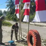 Personel Ops Madago Raya memasang umbul-umbul di saah satu ruas jalan di wilayah operasi di Poso, Jumat (1/6/2025). (©Huams Madago Raya)