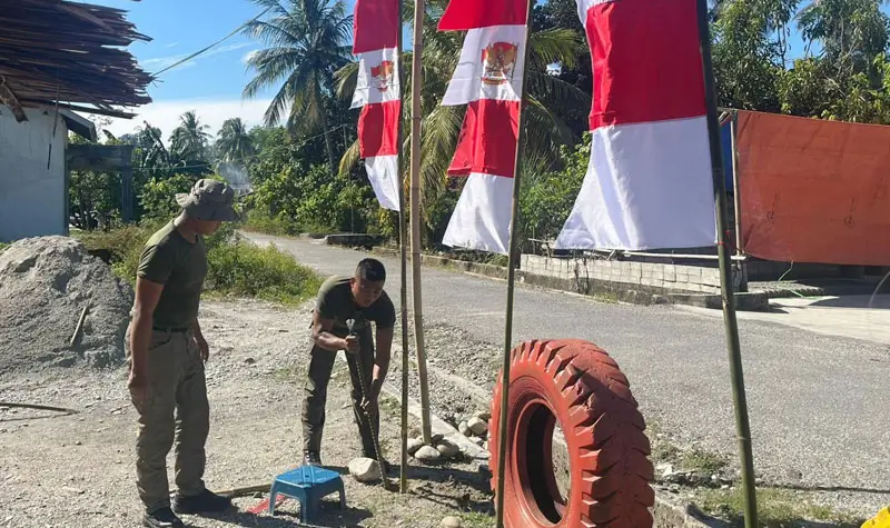 Personel Ops Madago Raya memasang umbul-umbul di saah satu ruas jalan di wilayah operasi di Poso, Jumat (1/6/2025). (©Huams Madago Raya)
